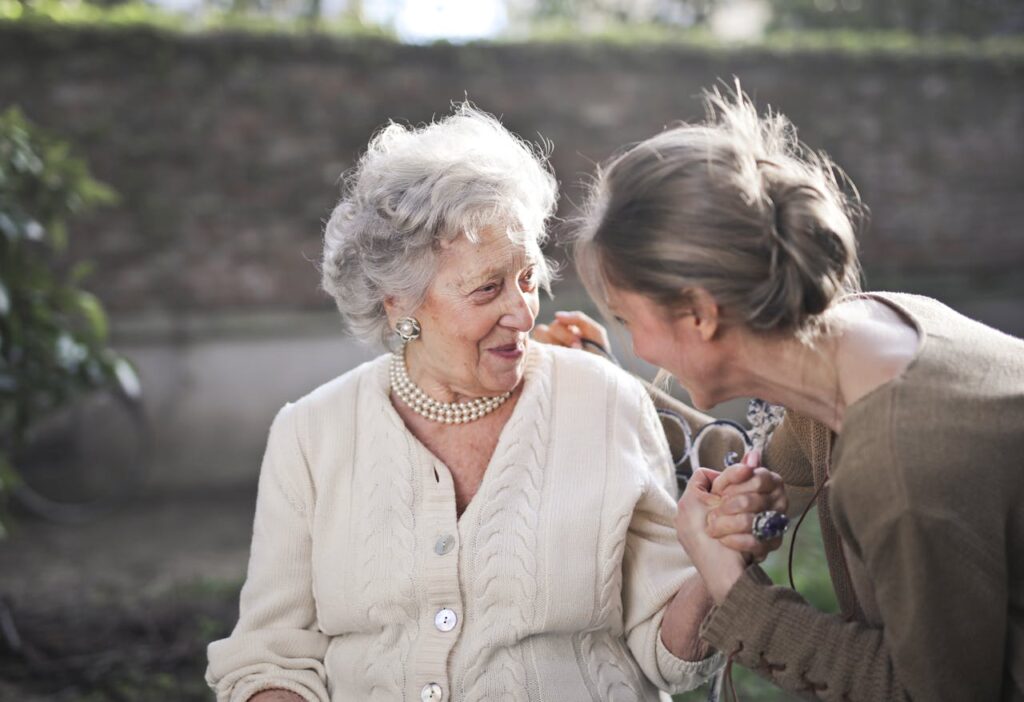 pexels photo 3768114 Joyful interaction between an elderly woman and her granddaughter in a sunny outdoor setting.