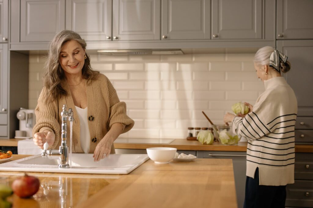pexels photo 6927898 Two senior women smiling and spending time together in a cozy kitchen.