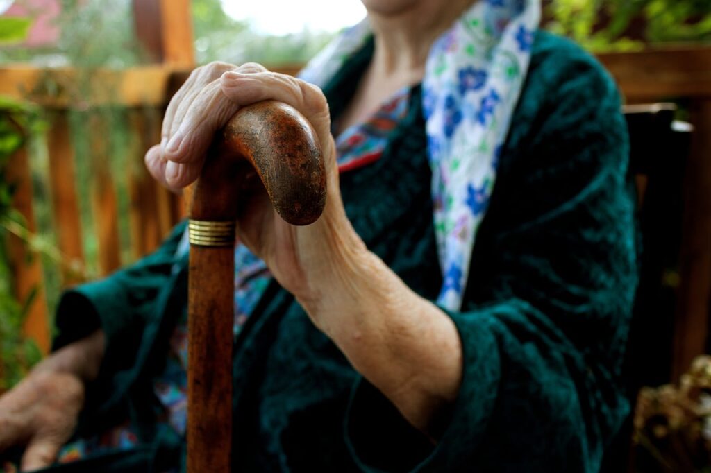 pexels photo 8677826 Senior adult holding a wooden cane, symbolizing strength and support.